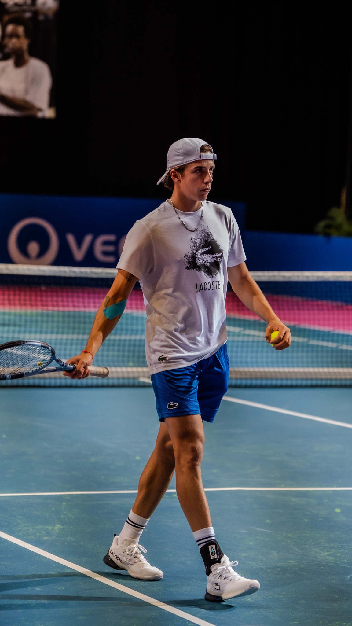 Jeune joueur concentré sur court de tennis intérieur bleu, séance ljdvision à Montpellier